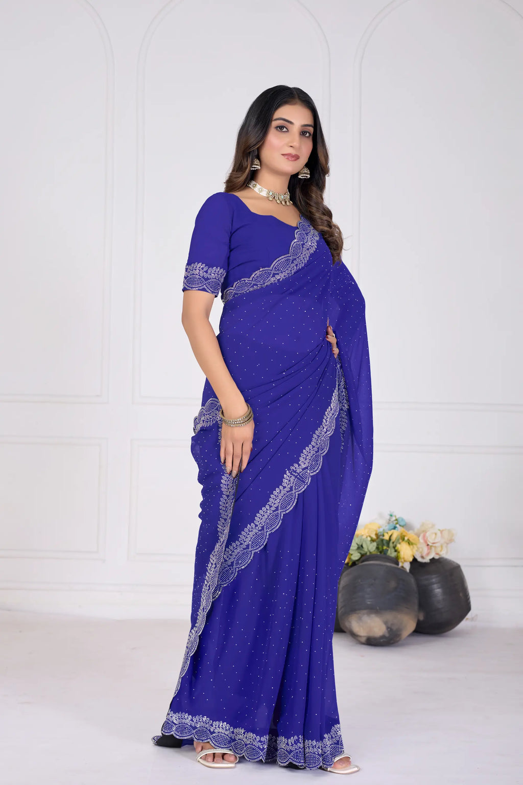 Woman wearing a blue saree with white lace details on a white background
