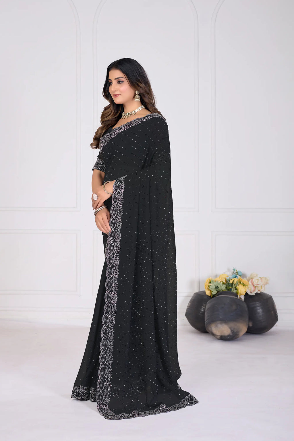 Woman wearing a black saree with white patterns against a white background
