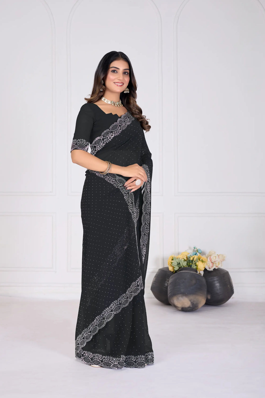 Woman wearing a black saree with silver border against a white background
