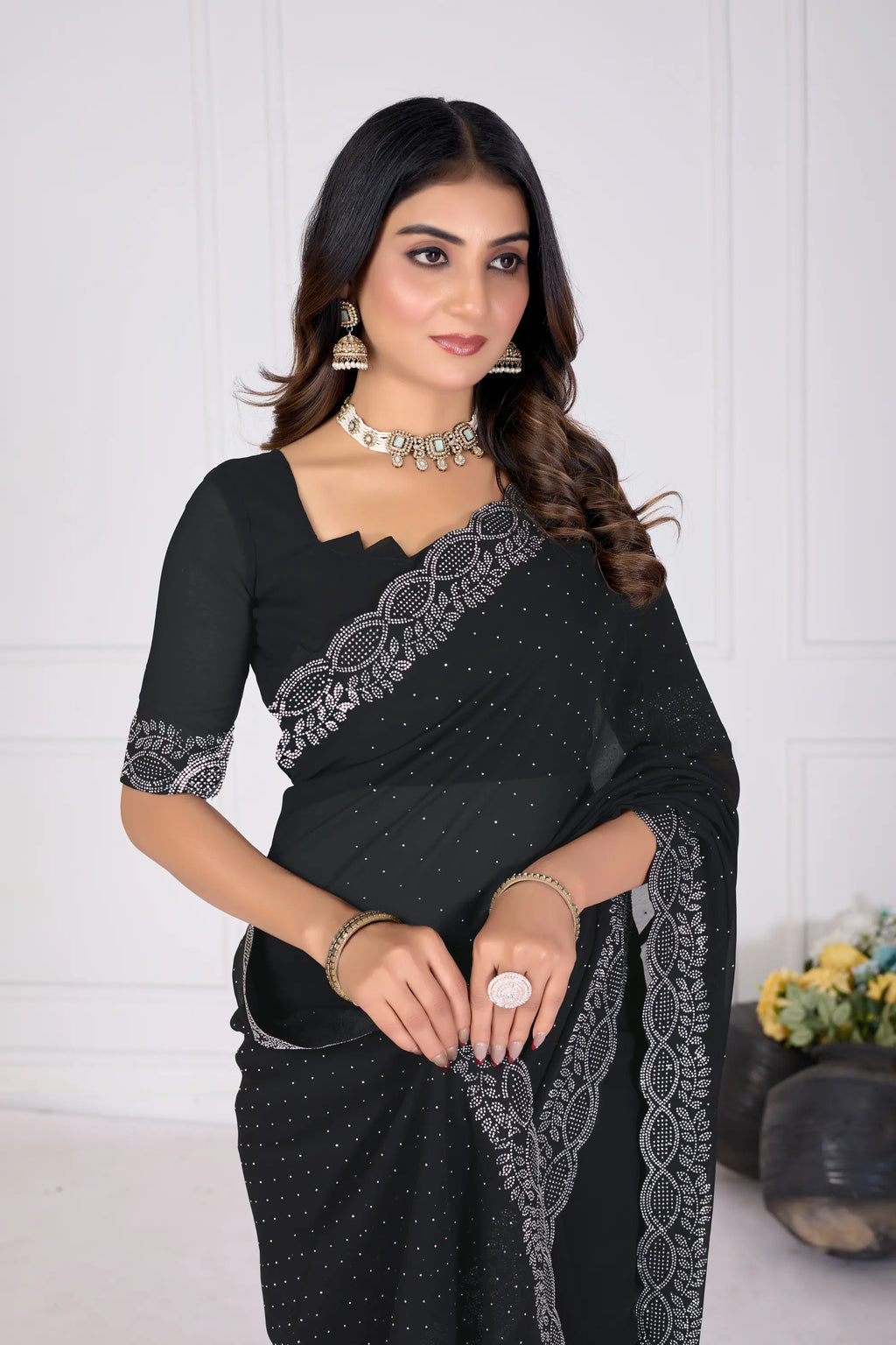 Woman wearing a black saree with silver embroidery against a white background