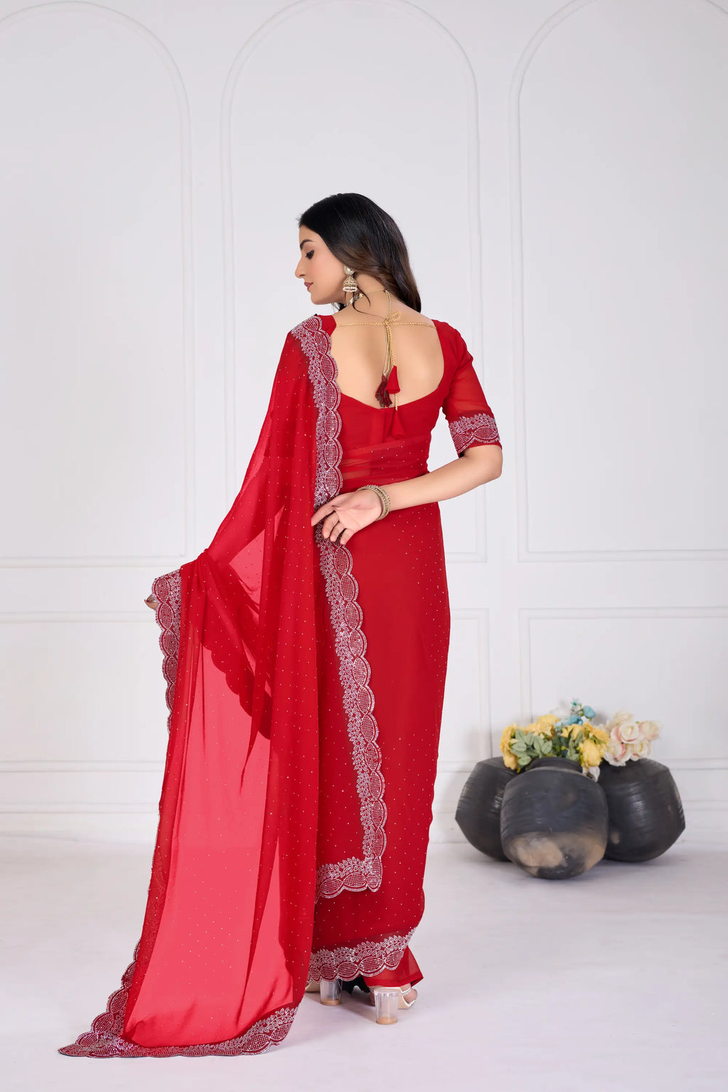 Woman wearing a red saree with a white border against a white background