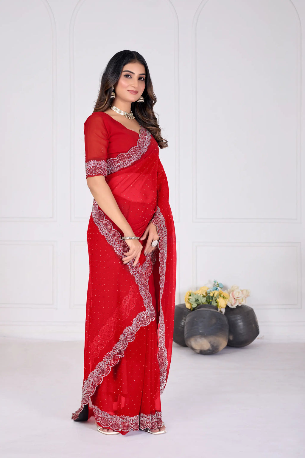 Woman wearing a red saree with white border against a white background