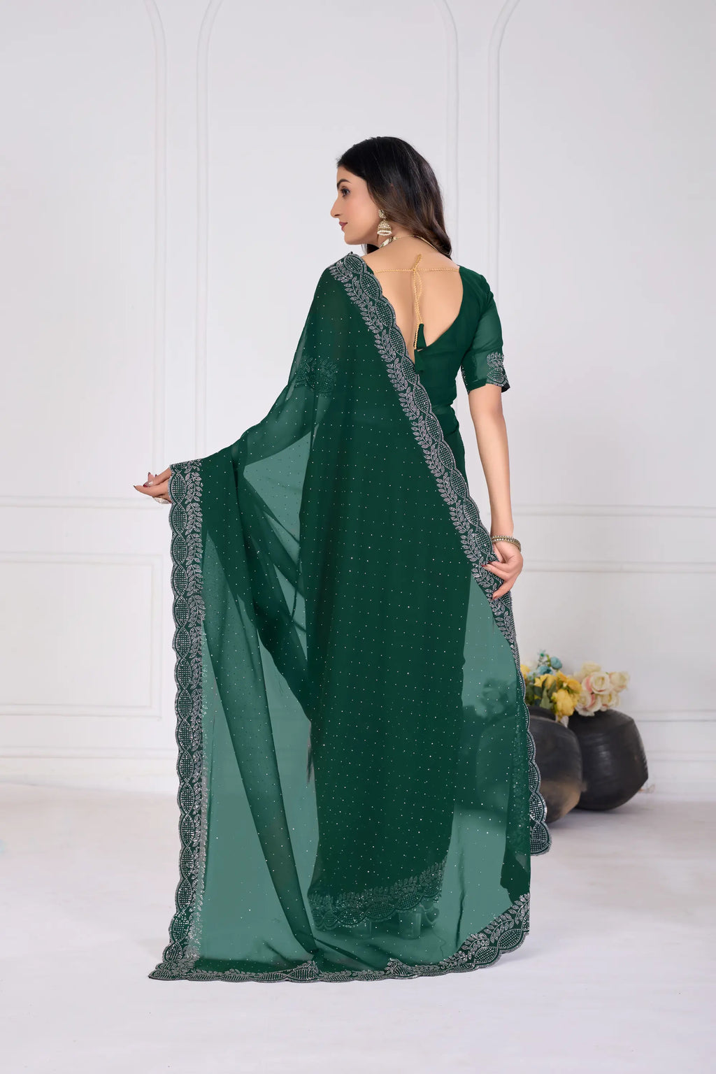 Woman wearing a green saree with silver border on a white background