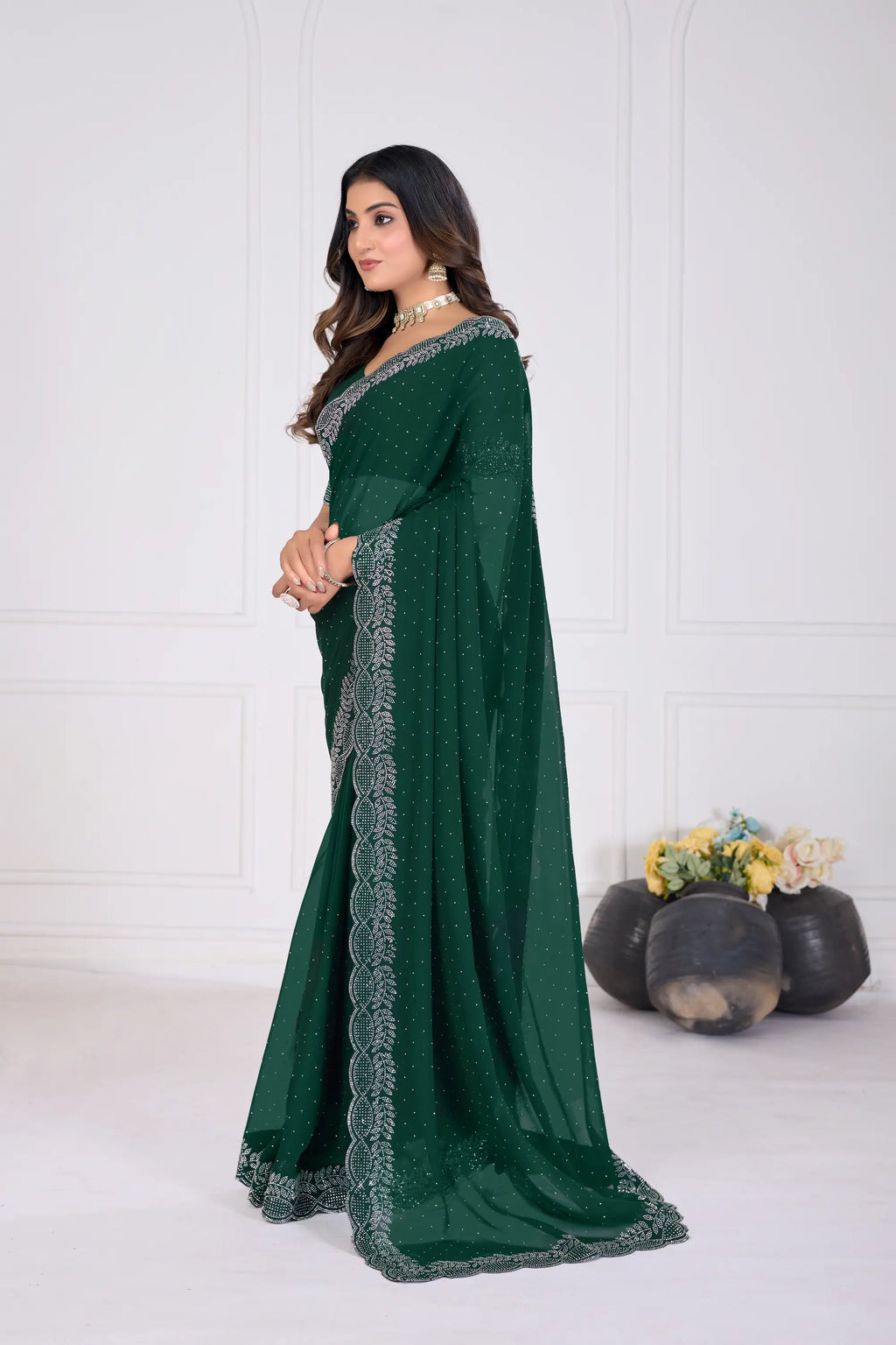 Woman wearing a green saree with silver border against a white background