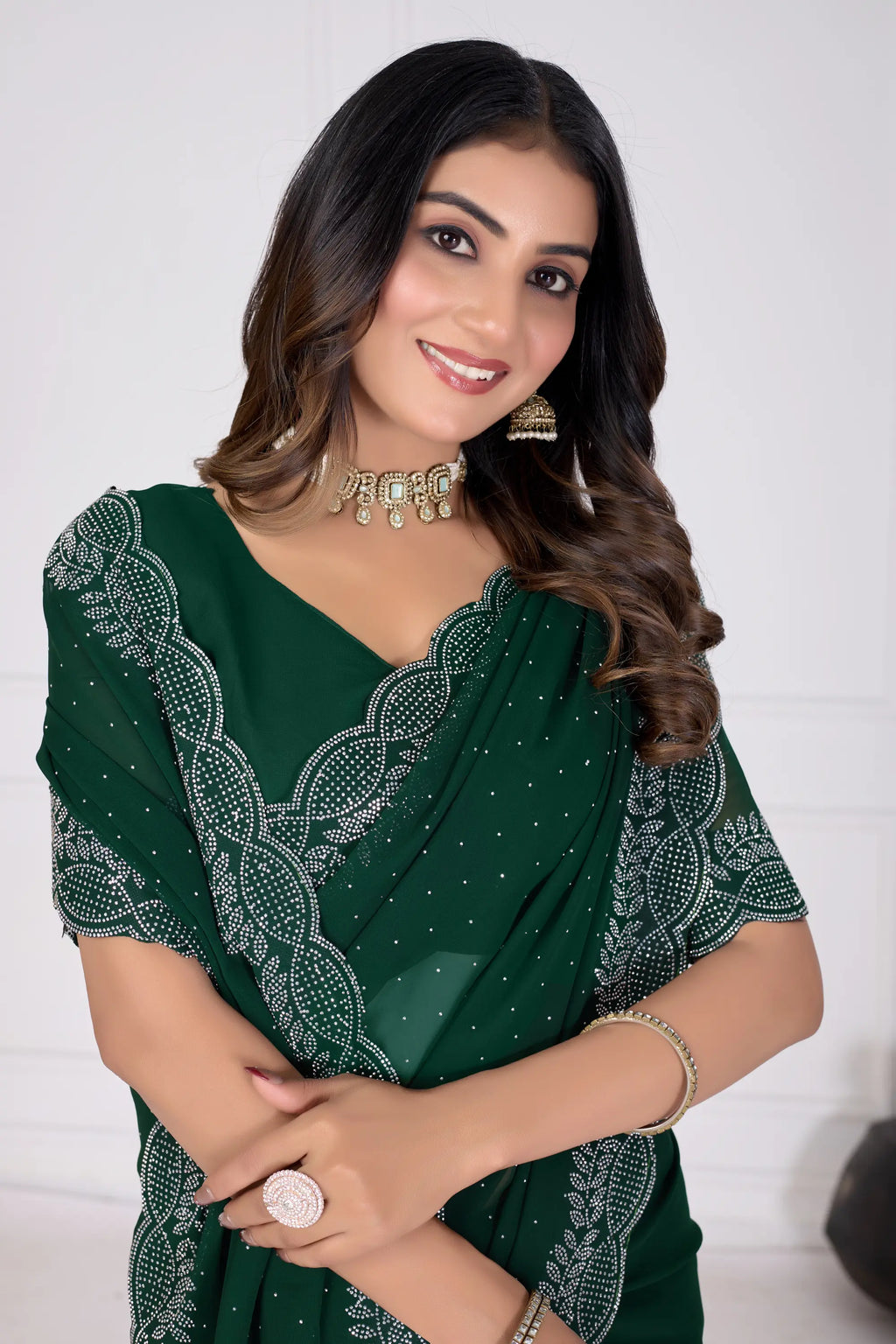 Woman wearing a green saree with white patterns on a white background