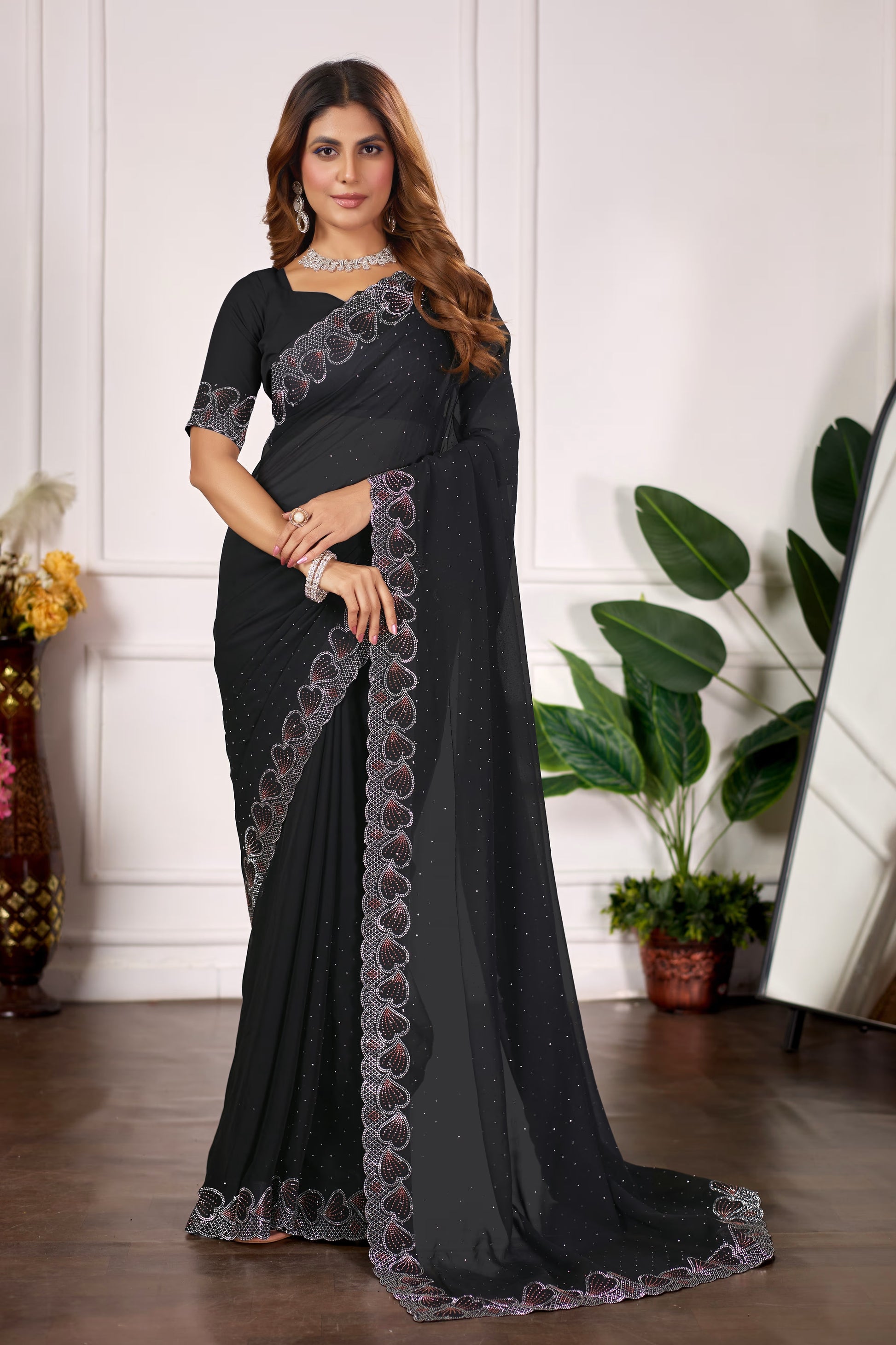 Woman wearing a black saree with floral patterns indoors.